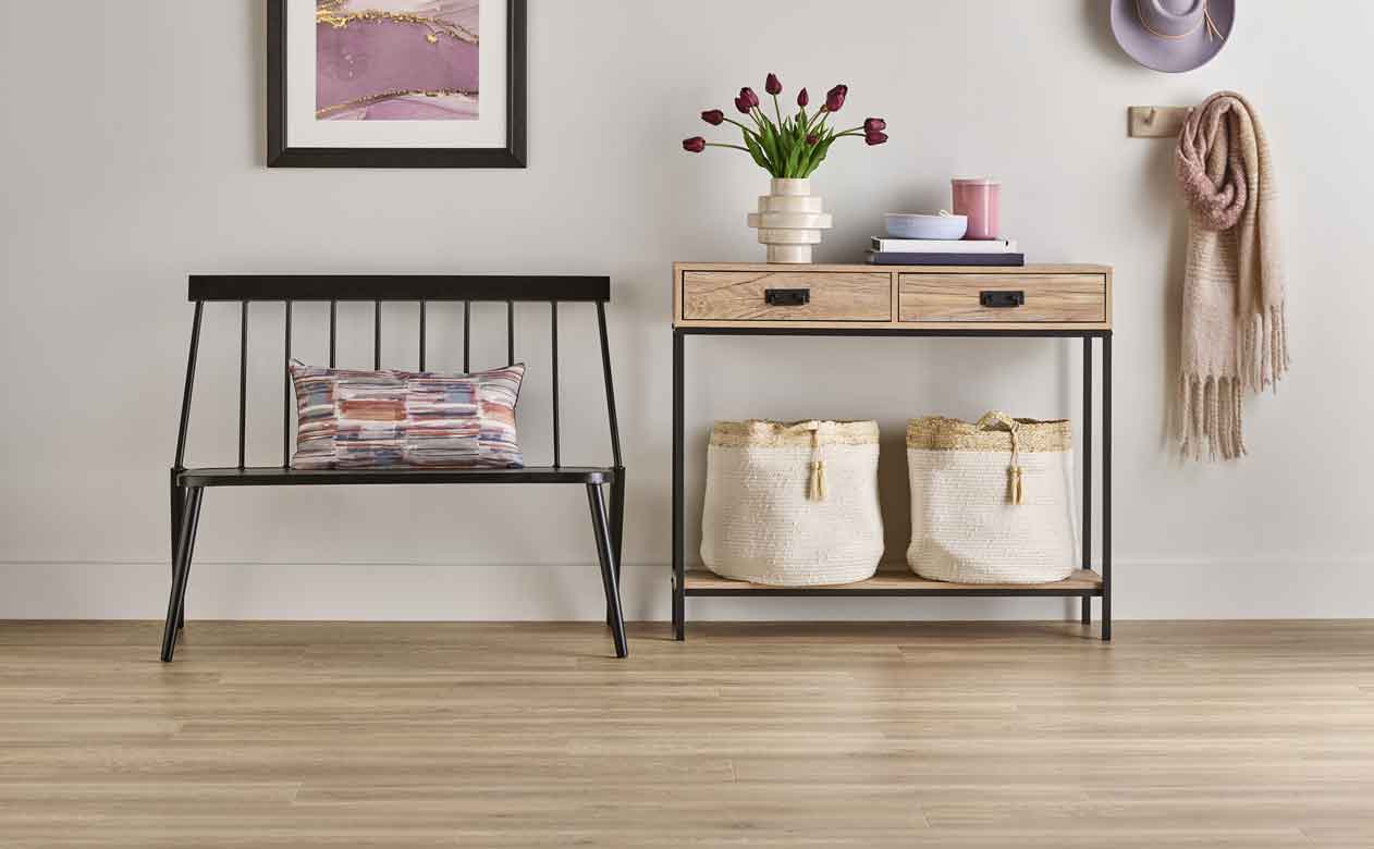 light wood-look laminate flooring in entryway with black bench and light wood console table