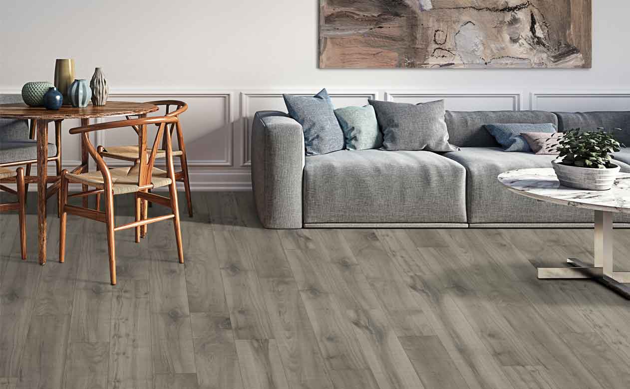 Grey wood look laminate flooring in living area with wood dining table and grey sofa